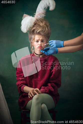 Image of Young woman as Marie Antoinette on dark background. Retro style, comparison of eras concept.