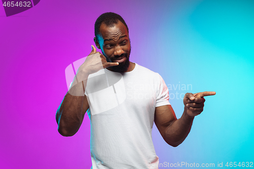 Image of African-american young man\'s portrait on gradient studio background in neon