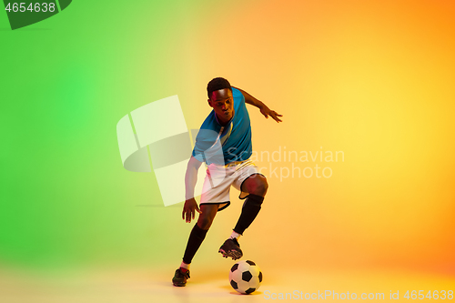 Image of Male soccer, football player training in action isolated on gradient studio background in neon light