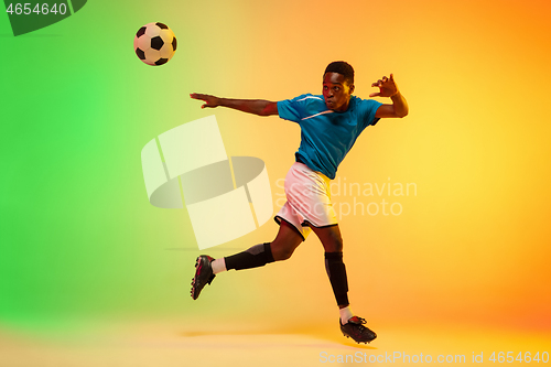 Image of Male soccer, football player training in action isolated on gradient studio background in neon light