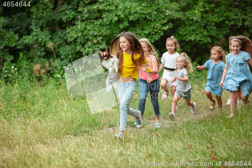 Image of Kids, children running on green meadow, forest. Childhood and summertime