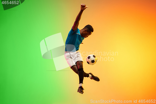 Image of Male soccer, football player training in action isolated on gradient studio background in neon light