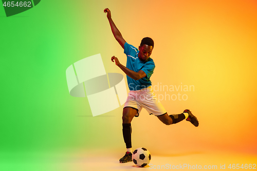 Image of Male soccer, football player training in action isolated on gradient studio background in neon light