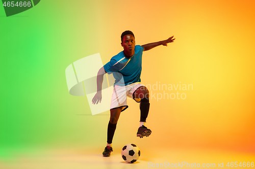 Image of Male soccer, football player training in action isolated on gradient studio background in neon light