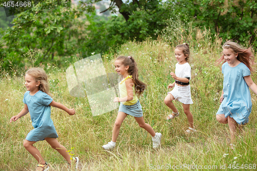 Image of Kids, children running on green meadow, forest. Childhood and summertime