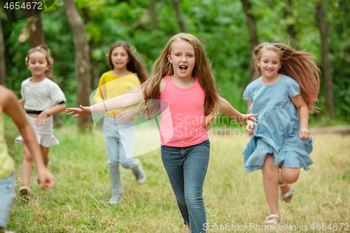 Image of Kids, children running on green meadow, forest. Childhood and summertime