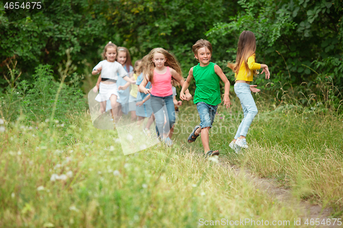 Image of Kids, children running on green meadow, forest. Childhood and summertime