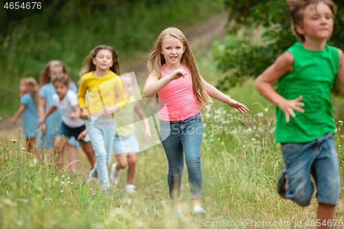 Image of Kids, children running on green meadow, forest. Childhood and summertime