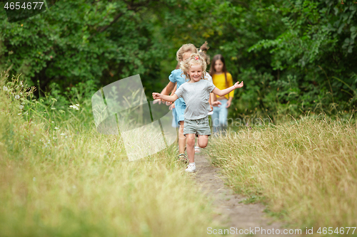 Image of Kids, children running on green meadow, forest. Childhood and summertime