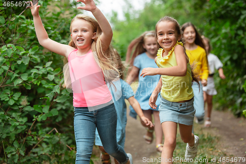 Image of Kids, children running on green meadow, forest. Childhood and summertime