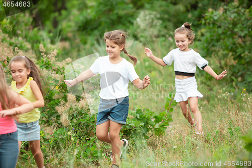 Image of Kids, children running on green meadow, forest. Childhood and summertime