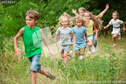 Image of Kids, children running on green meadow, forest. Childhood and summertime