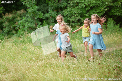 Image of Kids, children running on green meadow, forest. Childhood and summertime