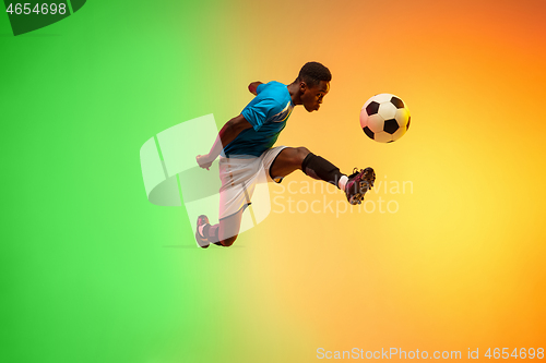 Image of Male soccer, football player training in action isolated on gradient studio background in neon light