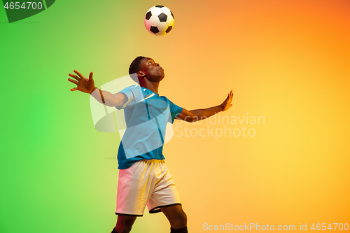 Image of Male soccer, football player training in action isolated on gradient studio background in neon light