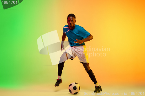 Image of Male soccer, football player training in action isolated on gradient studio background in neon light