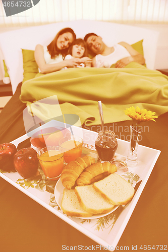 Image of happy young family eat breakfast in bed