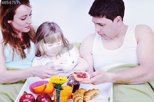 Image of happy young family eat breakfast in bed