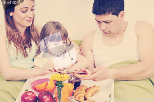 Image of happy young family eat breakfast in bed