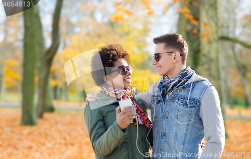 Image of couple with smartphone and earphones in autumn