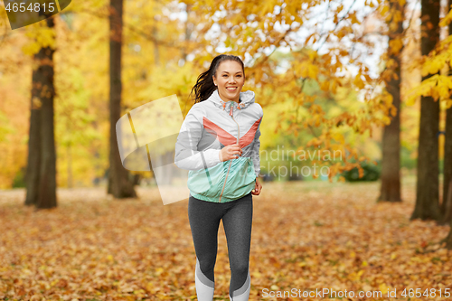 Image of young woman running in autumn park