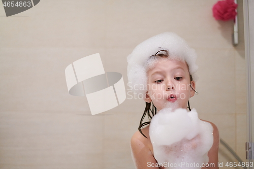 Image of little girl in bath playing with soap foam