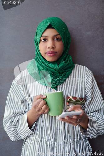 Image of african muslim businesswoman with green hijab using mobile phone