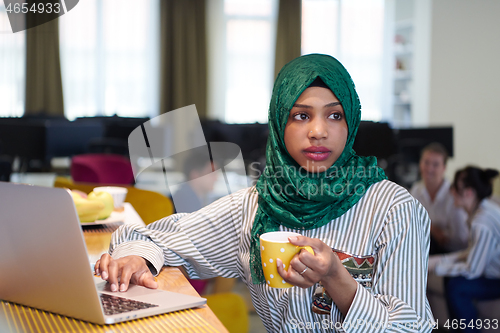 Image of african muslim business woman drinking tea