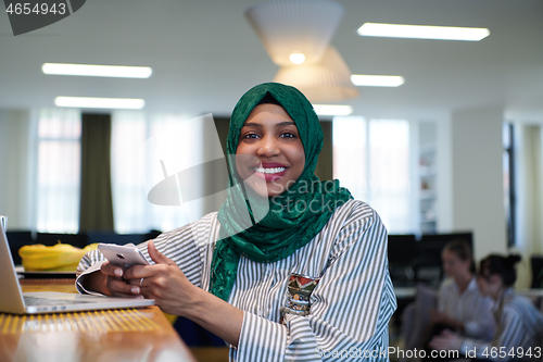 Image of african muslim business woman using mobile phone