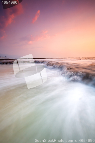 Image of Cascading waves flowing over the exposed rock shelf early mornin