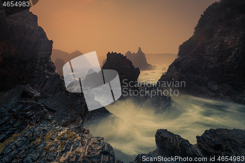 Image of Sea fog and sunrise on sharp craggy coastline