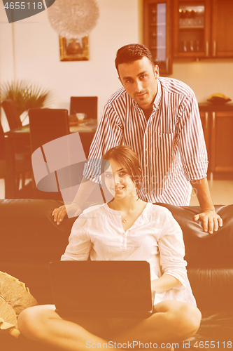 Image of joyful couple relax and work on laptop computer at modern home
