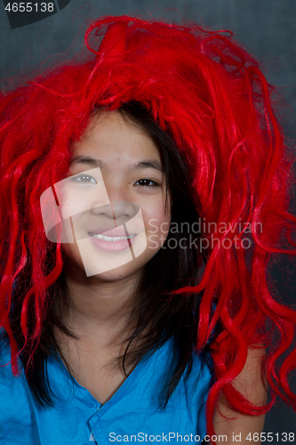 Image of Portrait of a young cute girl with false red hair  looking at th