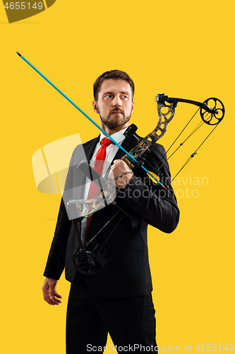 Image of Businessman aiming at target with bow and arrow, isolated on yellow background