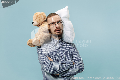 Image of Tired man sleeping at home having too much work. Bored businessman with pillow and toy bear