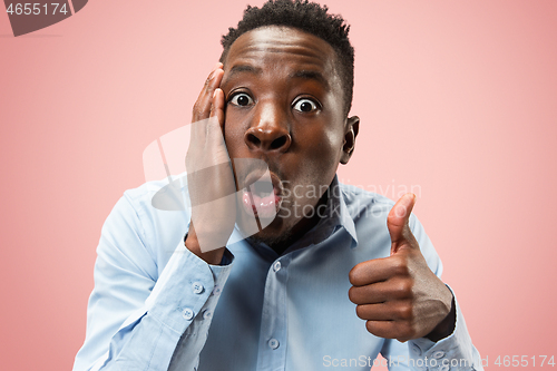 Image of The young attractive man looking suprised isolated on pink