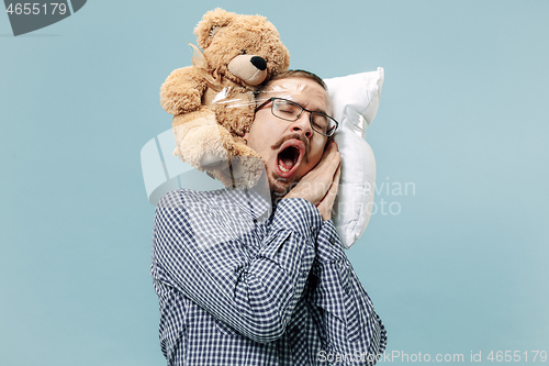 Image of Tired man sleeping at home having too much work. Bored businessman with pillow and toy bear