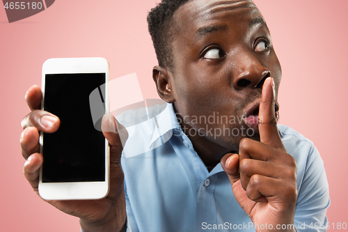 Image of Indoor portrait of attractive young black man holding blank smartphone