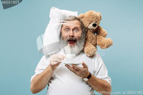 Image of Tired man sleeping at home having too much work. Bored businessman with pillow and toy bear