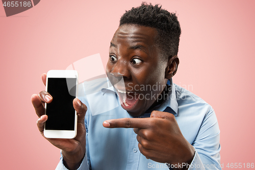 Image of Indoor portrait of attractive young black man holding blank smartphone