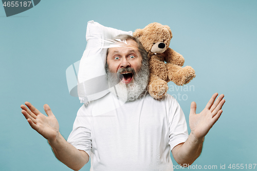 Image of Tired man sleeping at home having too much work. Bored businessman with pillow and toy bear