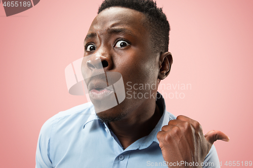 Image of The young attractive man looking suprised isolated on pink