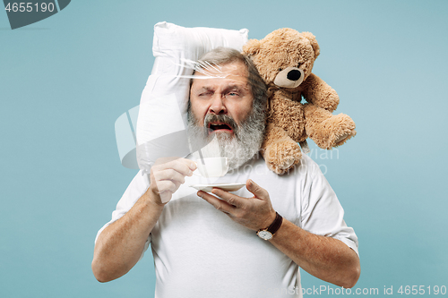 Image of Tired man sleeping at home having too much work. Bored businessman with pillow and toy bear