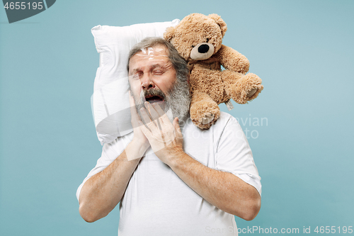 Image of Tired man sleeping at home having too much work. Bored businessman with pillow and toy bear