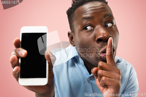 Image of Indoor portrait of attractive young black man holding blank smartphone