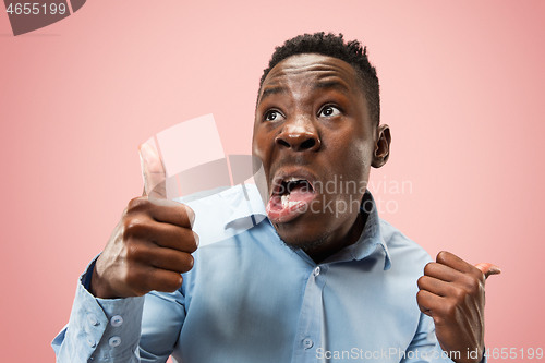 Image of The young attractive man looking suprised isolated on pink