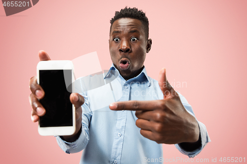 Image of Indoor portrait of attractive young black man holding blank smartphone