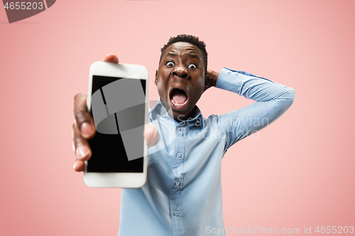 Image of Indoor portrait of attractive young black man holding blank smartphone