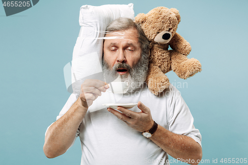 Image of Tired man sleeping at home having too much work. Bored businessman with pillow and toy bear