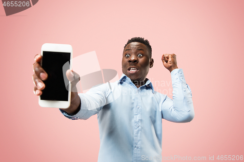 Image of Indoor portrait of attractive young black man holding blank smartphone